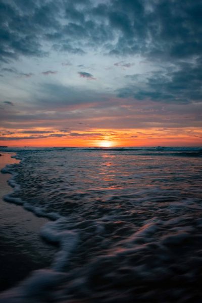 The sunset over the ocean paints vibrant colors on the tranquil waves, creating a serene and beautiful view